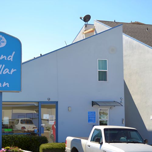 A blue building with a blue sign, a white truck, and a partial street scene.