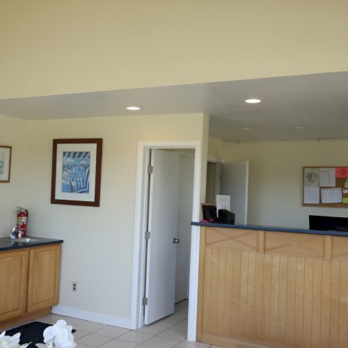 A bright, modern living area with a wooden bar or counter, open shelves, a kitchen island, and soft natural light.